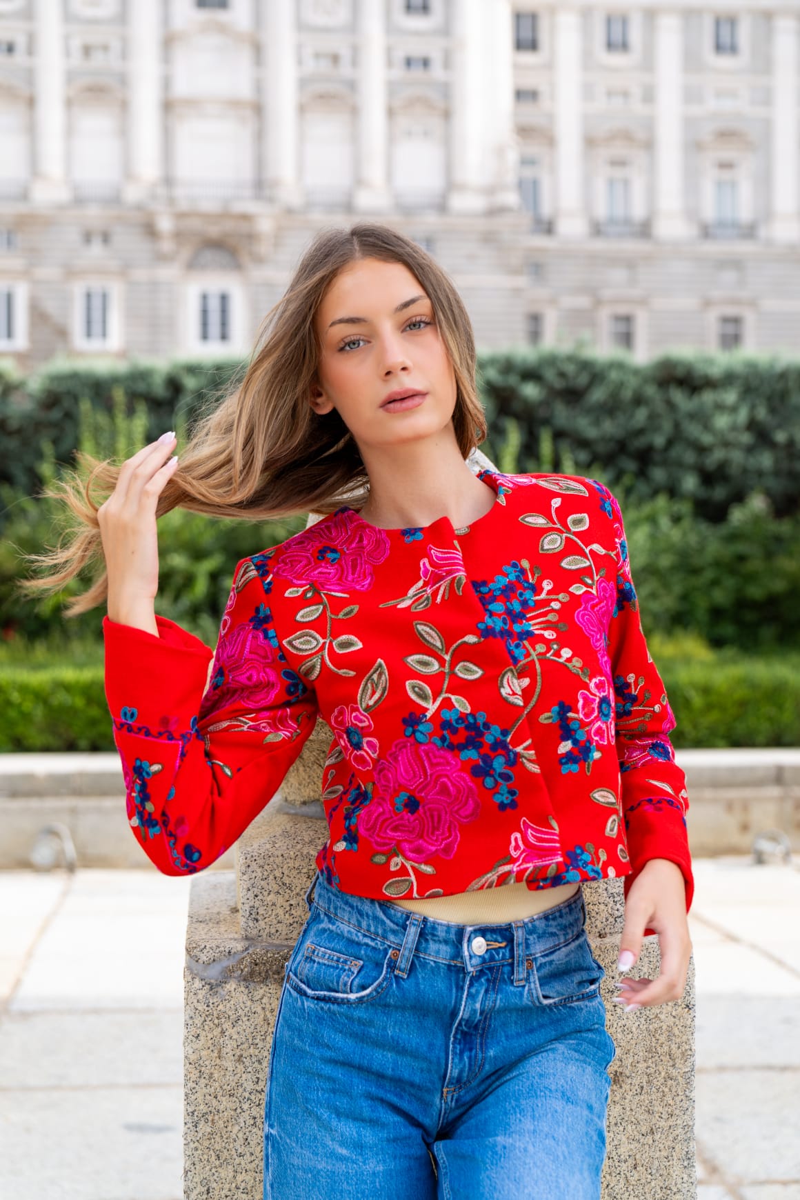 Torera roja bordada con flores fucsia y azules frente al Palacio Real de Madrid