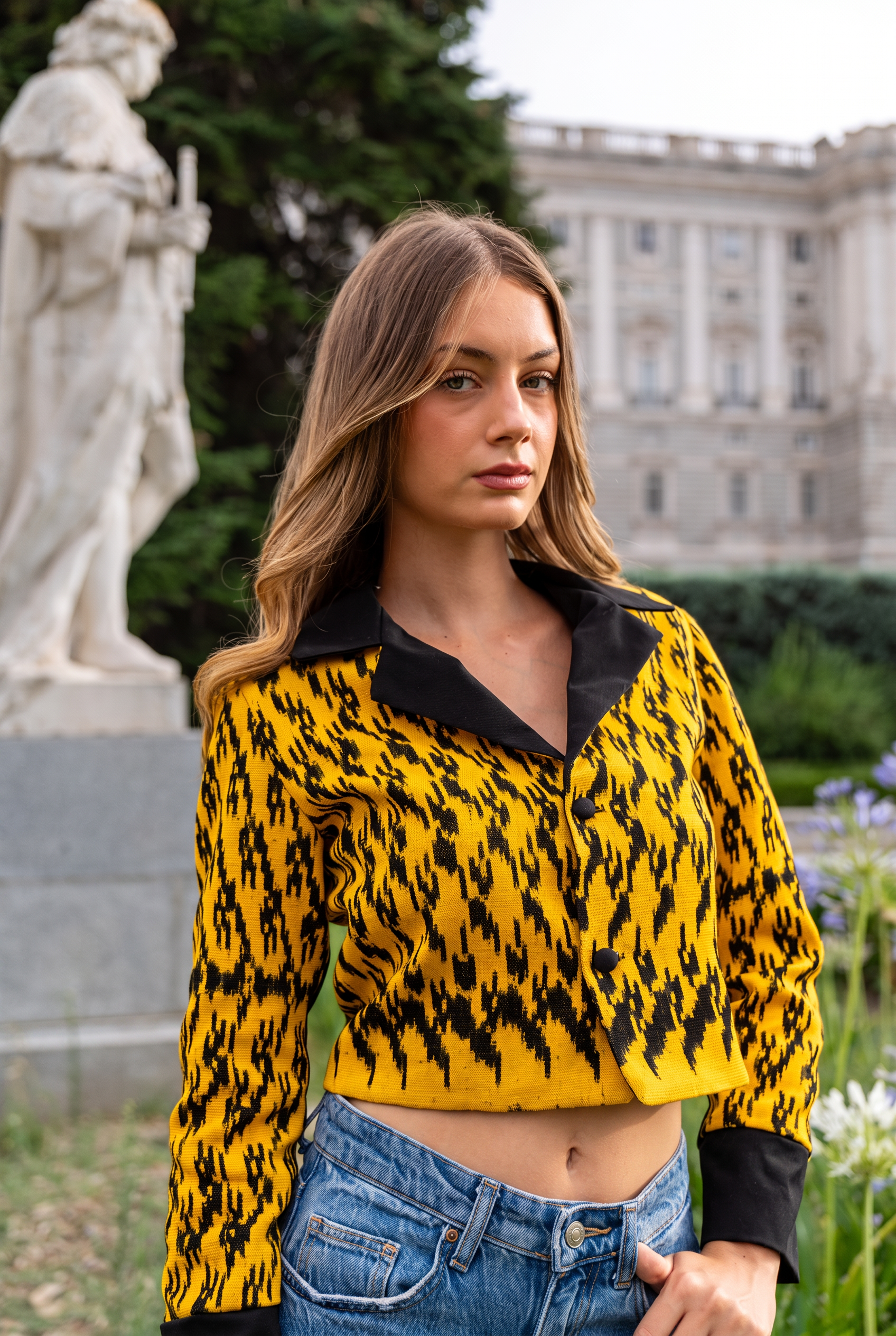 Torera ikat amarillo azafrán y negro con cuello camisero, retrato frente al Palacio Real de Madrid junto a estatua clásica