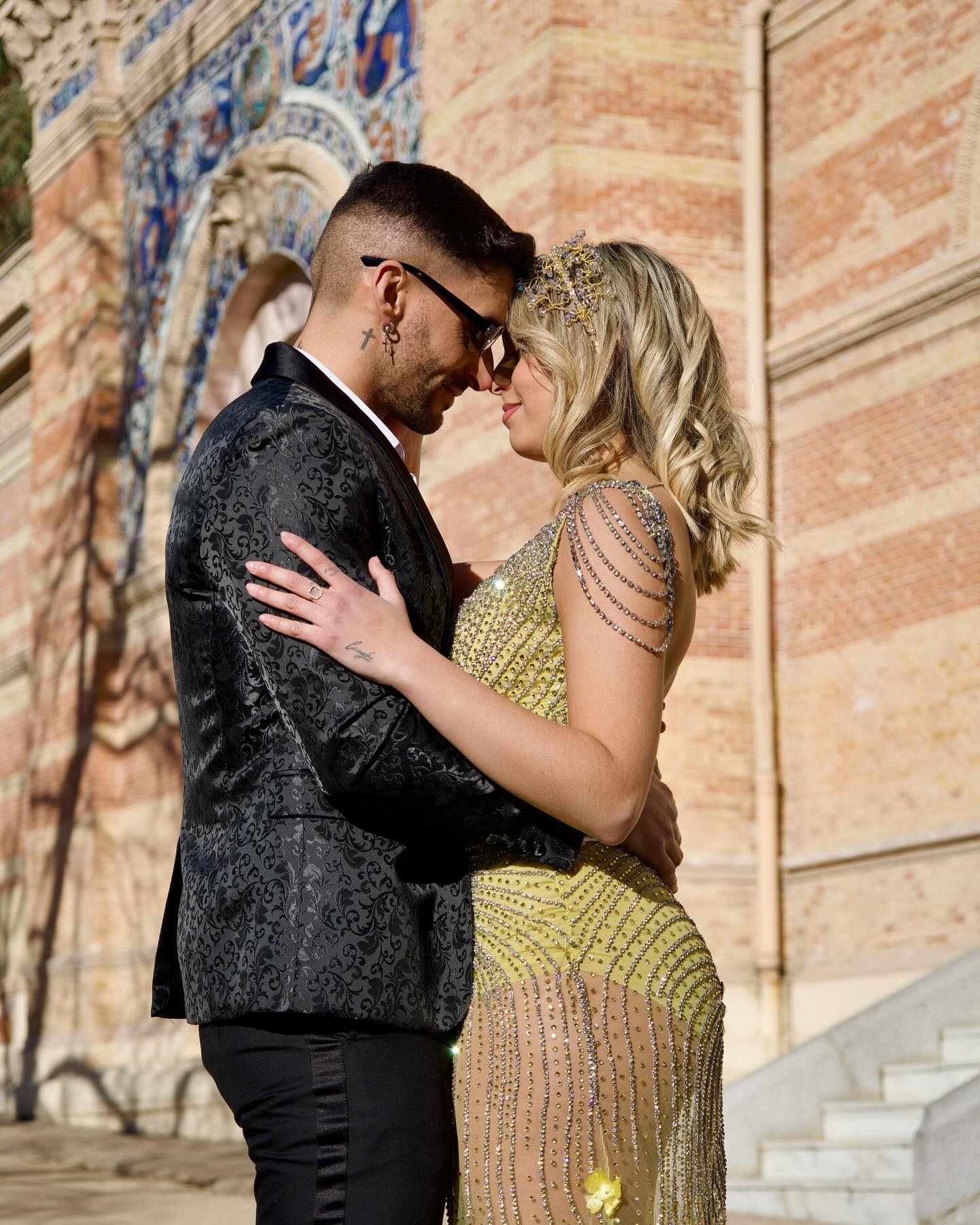 Traje de novio en jacquard negro junto a vestido dorado con pedrería