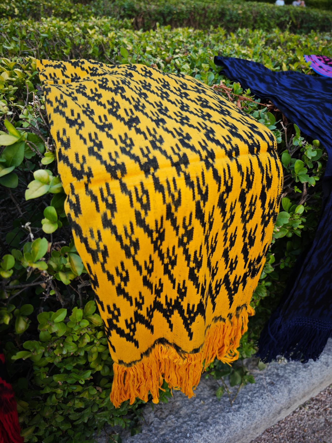 Bufanda ikat amarillo azafrán con motivos negros y flecos, tejida a mano en Cuenca, Ecuador