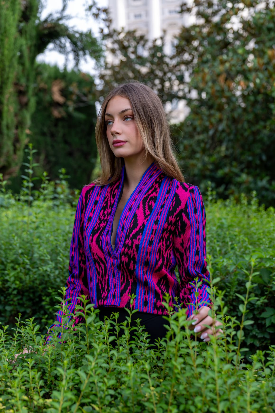 Torera ikat fucsia, azul eléctrico y negro con escote en V, retrato en jardines de Madrid