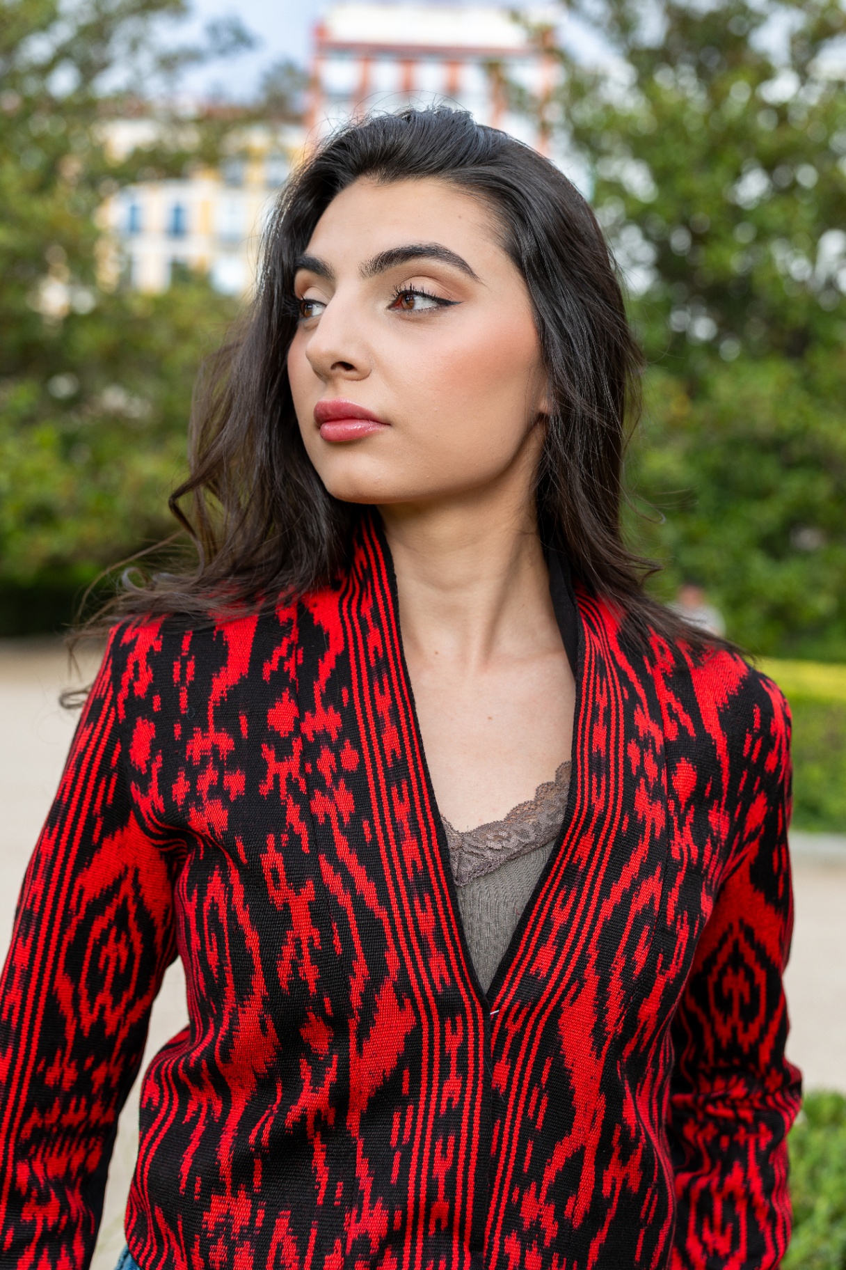 Torera ikat roja y negra con vivos de raso negro, retrato de perfil en jardín de Madrid