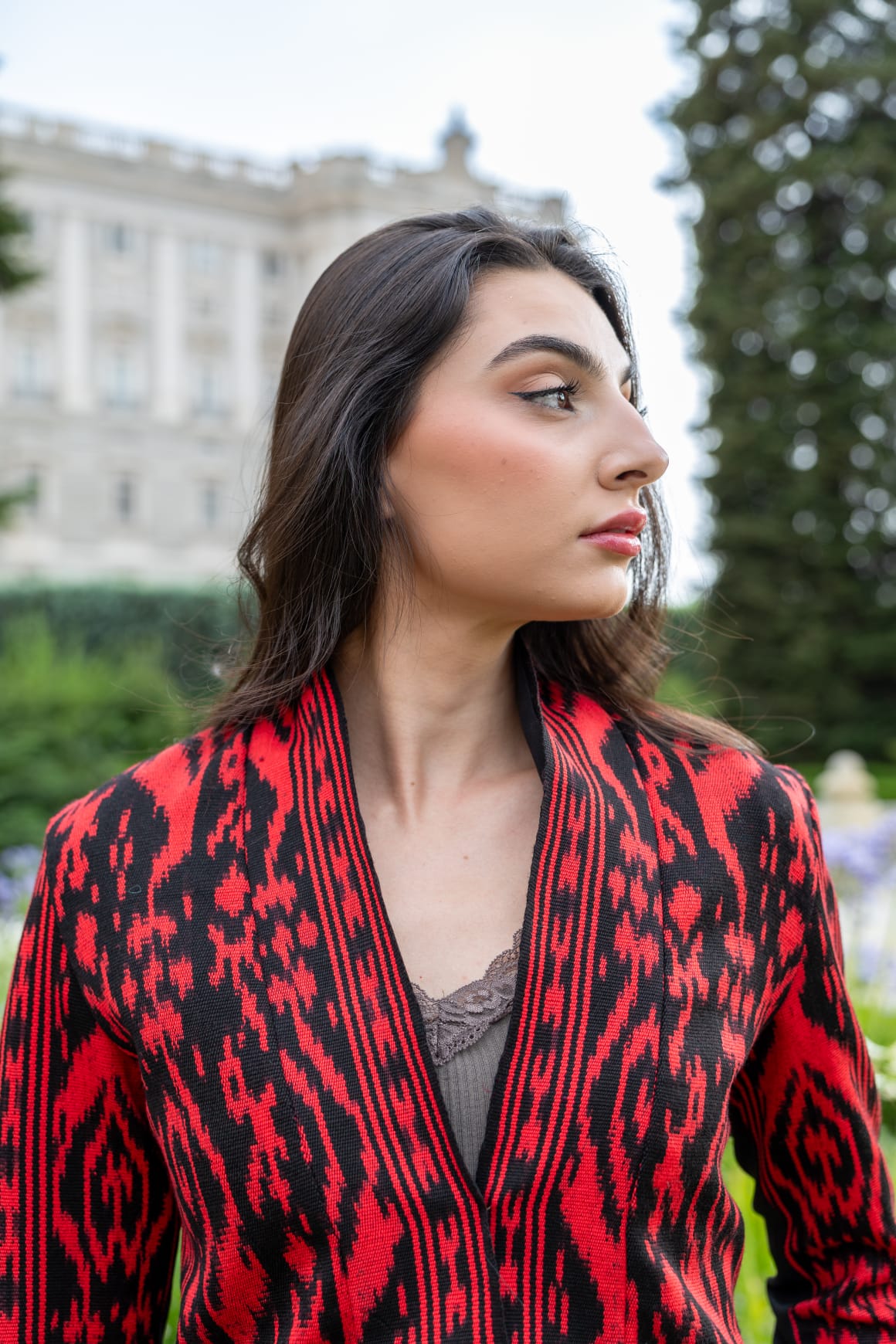 Torera ikat roja y negra cruzada en V, retrato de perfil frente al Palacio Real de Madrid